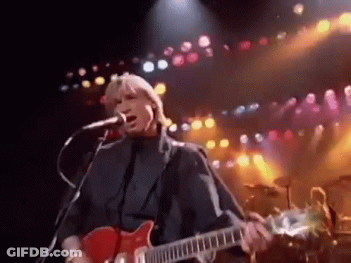 Man Singing Into Microphone And Playing Guitar On Stage GIF