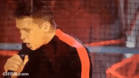 Man Singing Into Microphone In Black And Red Jacket GIF