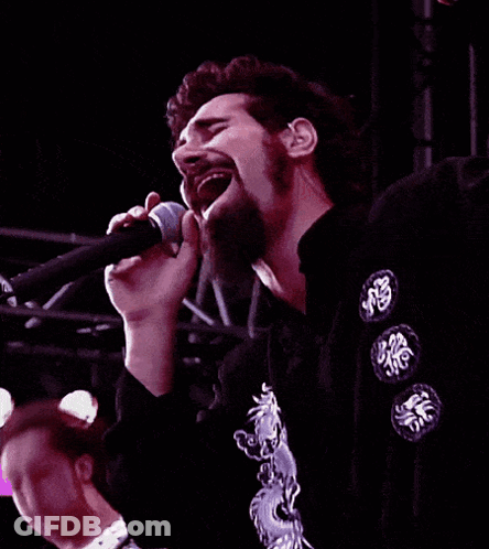 Man Singing Into Microphone In Black Shirt With Chinese Symbols GIF