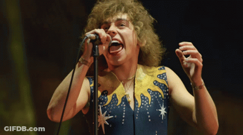 Man Singing Into Microphone In Blue And Yellow Outfit GIF