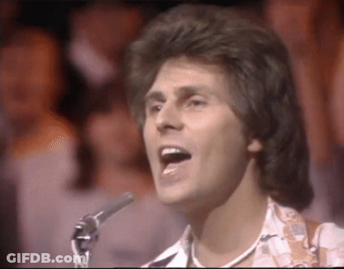 Man Singing Into Microphone In Front Of Crowd GIF