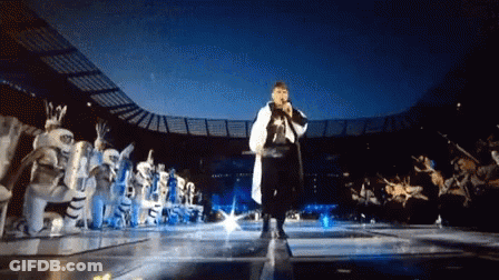Man Singing Into Microphone In Front Of Crowd GIF