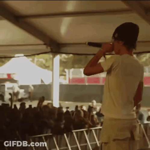 Man Singing Into Microphone In Front Of Crowd GIF