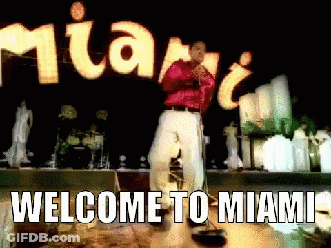 Man Singing Into Microphone In Front Of Welcome To Miami Sign GIF
