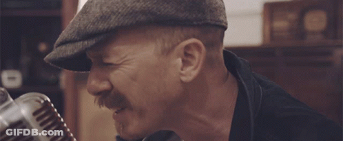 Man Singing Into Microphone In Hat And Black Jacket GIF