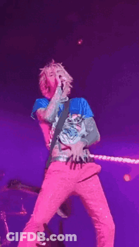Man Singing Into Microphone In Pink Pants And Blue Shirt GIF