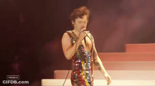 Man Singing Into Microphone In Sequined Outfit GIF