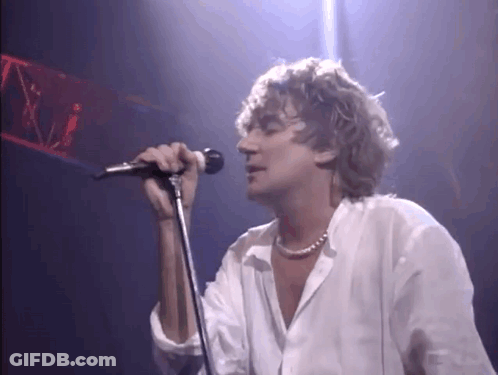 Man Singing Into Microphone On Stage In Dark Room GIF
