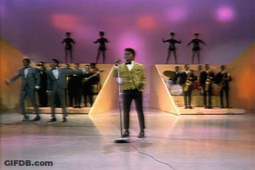 Man Singing Into Microphone On Stage With Band GIF