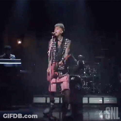 Man Singing Into Microphone On Stage With SNL Logo GIF