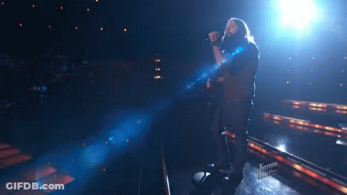 Man Singing Into Microphone On Stage With Team Voice Logo GIF