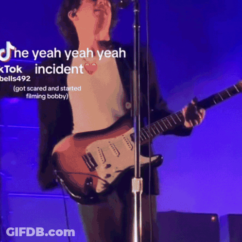 Man Singing Into Microphone Playing Guitar Purple Background GIF