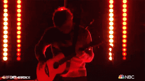Man Singing Into Microphone Playing Guitar With NBC Logo GIF