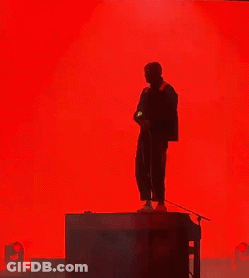 Man Singing Into Microphone Red Backdrop GIF