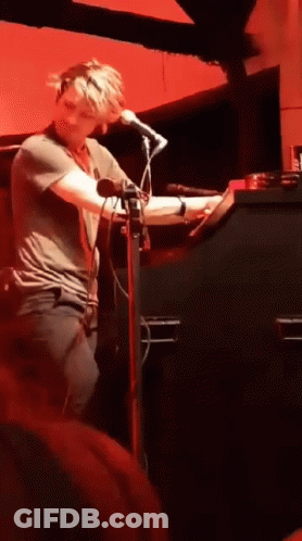 Man Singing Into Microphone Red Wall GIF