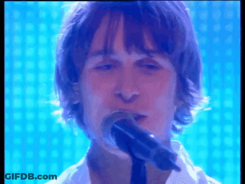 Man Singing Into Microphone With Blue Background GIF