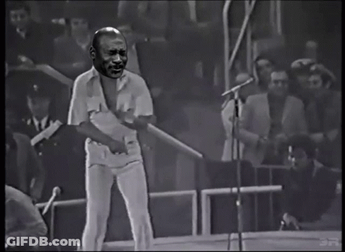 Man Singing Into Microphone With Crowd Behind GIF