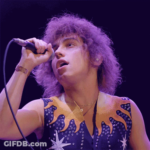 Man Singing Into Microphone With Star Vest GIF
