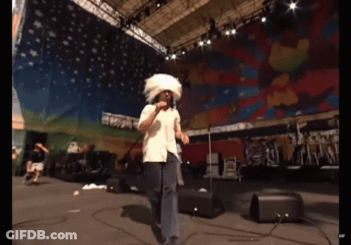 Man Singing Into Microphone With White Feathered Hat GIF