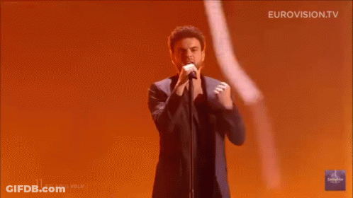 Man Singing On Stage With Hands In Air GIF