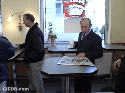 Man Sits At Table With Newspaper In Front Of Window With Burger Sign GIF