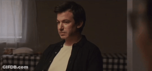 Man Sitting At Checkered Table Talking To Another Man GIF
