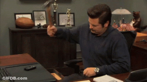 Man Sitting At Desk Holding Hammer GIF