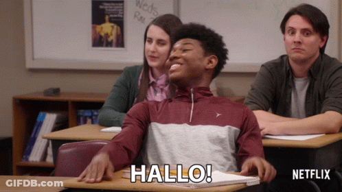 Man Sitting At Desk In Classroom Saying Hallo GIF
