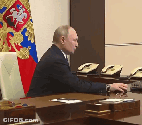 Man Sitting At Desk In Front Of Flag GIF