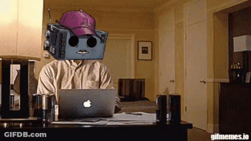 Man Sitting At Desk With Apple Laptop And Robot On Head GIF