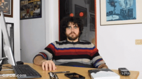 Man Sitting At Desk With Computer And Book GIF