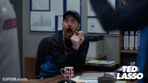 Man Sitting At Desk With Ted Lasso Logo GIF