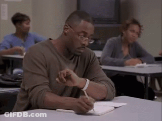 Man Sitting At Desk Writing In Notebook GIF