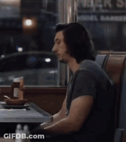 Man Sitting At Diner Table Looking At Cell Phone GIF