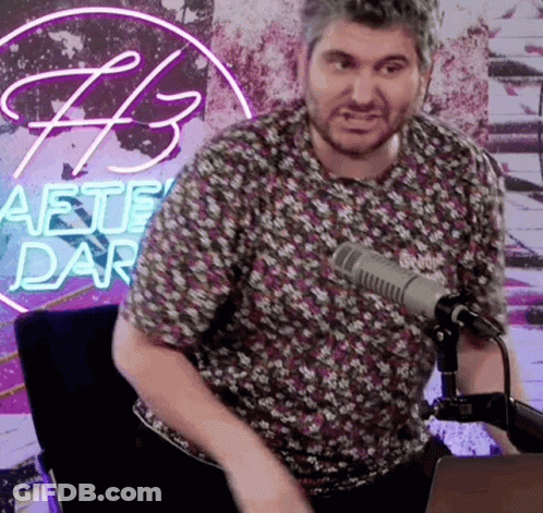 Man Sitting At Microphone In Front Of Aete Dar Neon Sign GIF