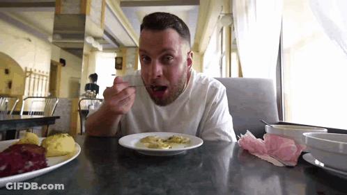 Man Sitting At Table Eating With Spoon GIF