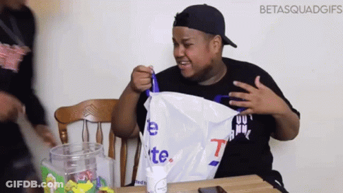 Man Sitting At Table Holding Bag Saying T GIF