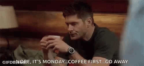 Man Sitting At Table Holding Coffee Talking To Another Man GIF
