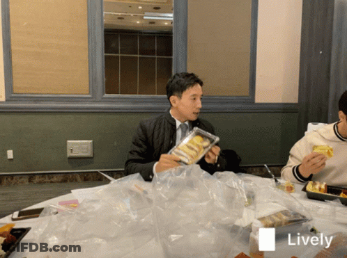 Man Sitting At Table Holding Food Package Saying Lively GIF