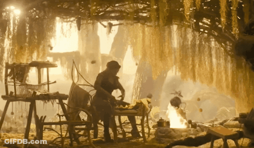 Man Sitting At Table In Cave With Fire GIF