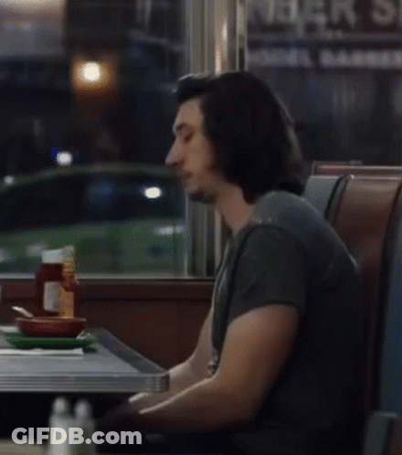 Man Sitting At Table In Front Of Bar Sign GIF