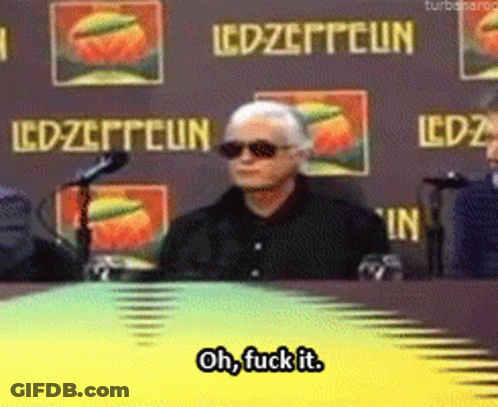 Man Sitting At Table In Front Of Led Zeppelin Sign GIF