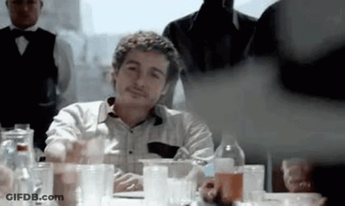Man Sitting At Table With Alcohol Bottles And Glasses GIF