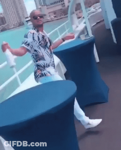 Man Sitting At Table With Arms Outstretched By Water GIF