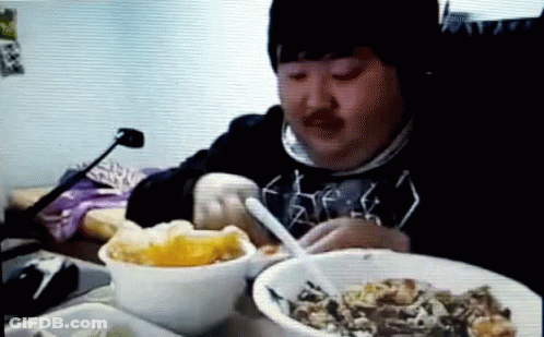 Man Sitting At Table With Bowls Of Food And Spoon GIF