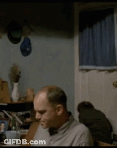 Man Sitting At Table With Hat On Wall GIF