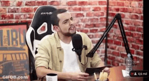 Man Sitting At Table With Microphone GIF