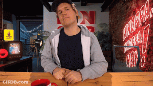 Man Sitting At Table With Neon NN Sign GIF
