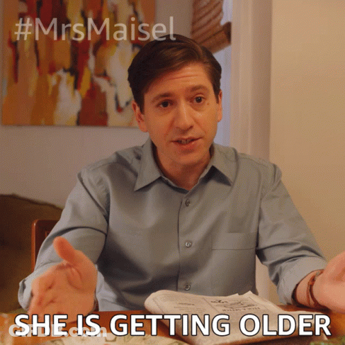 Man Sitting At Table With Newspaper Saying She Is Getting Older GIF