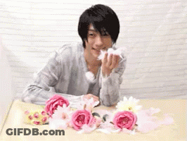 Man Sitting At Table With Pink Flowers GIF